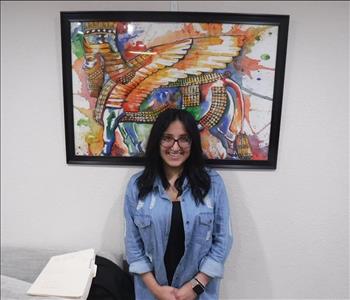 female office employee standing in front of a picture frame in office.